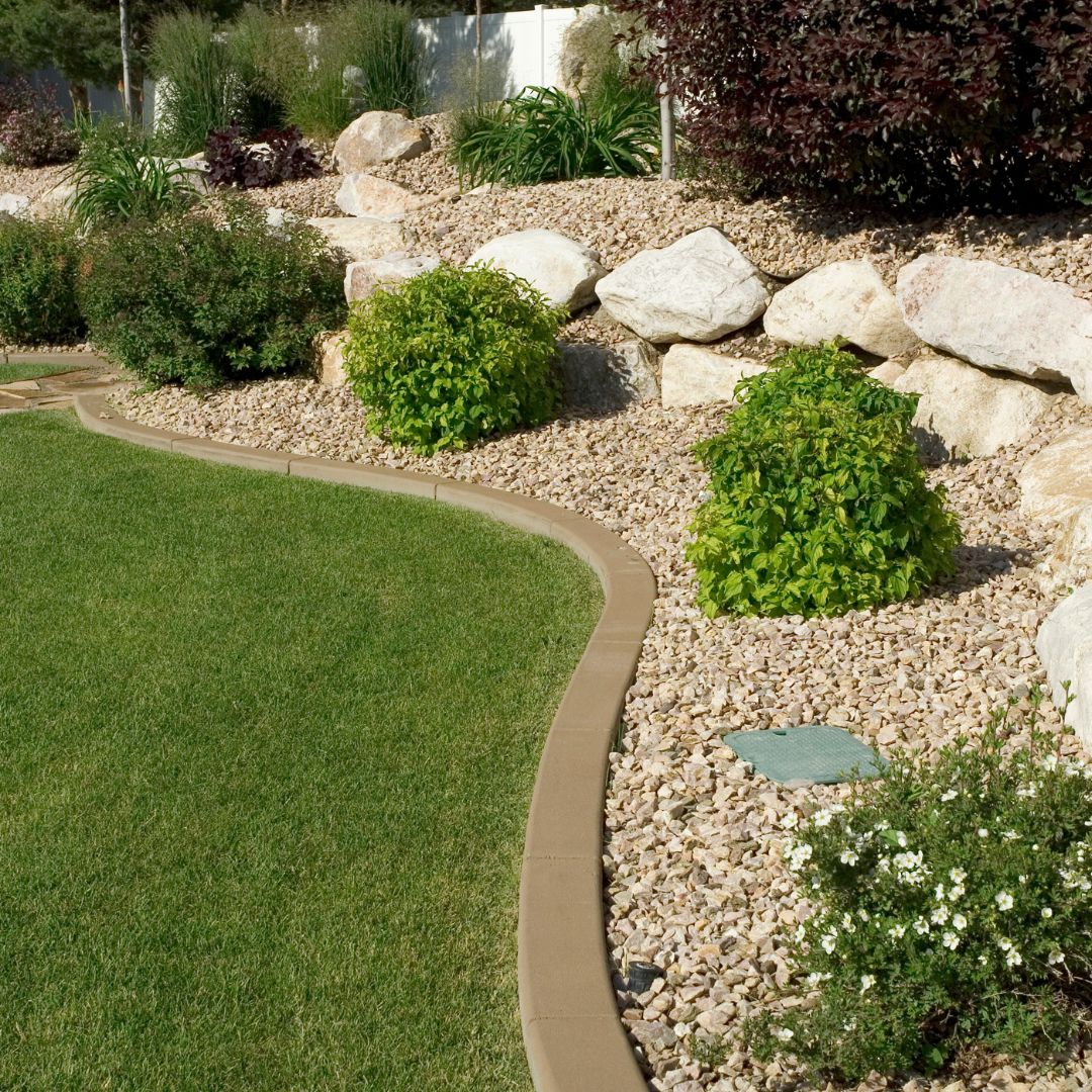 Landscaped garden with green lawn, rocks, gravel, and round shrubs