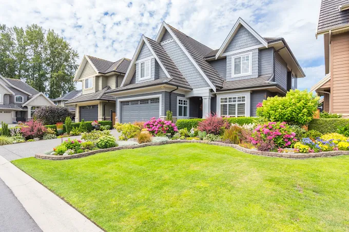 Well-manicured suburban houses with colorful landscaped garden and green lawn