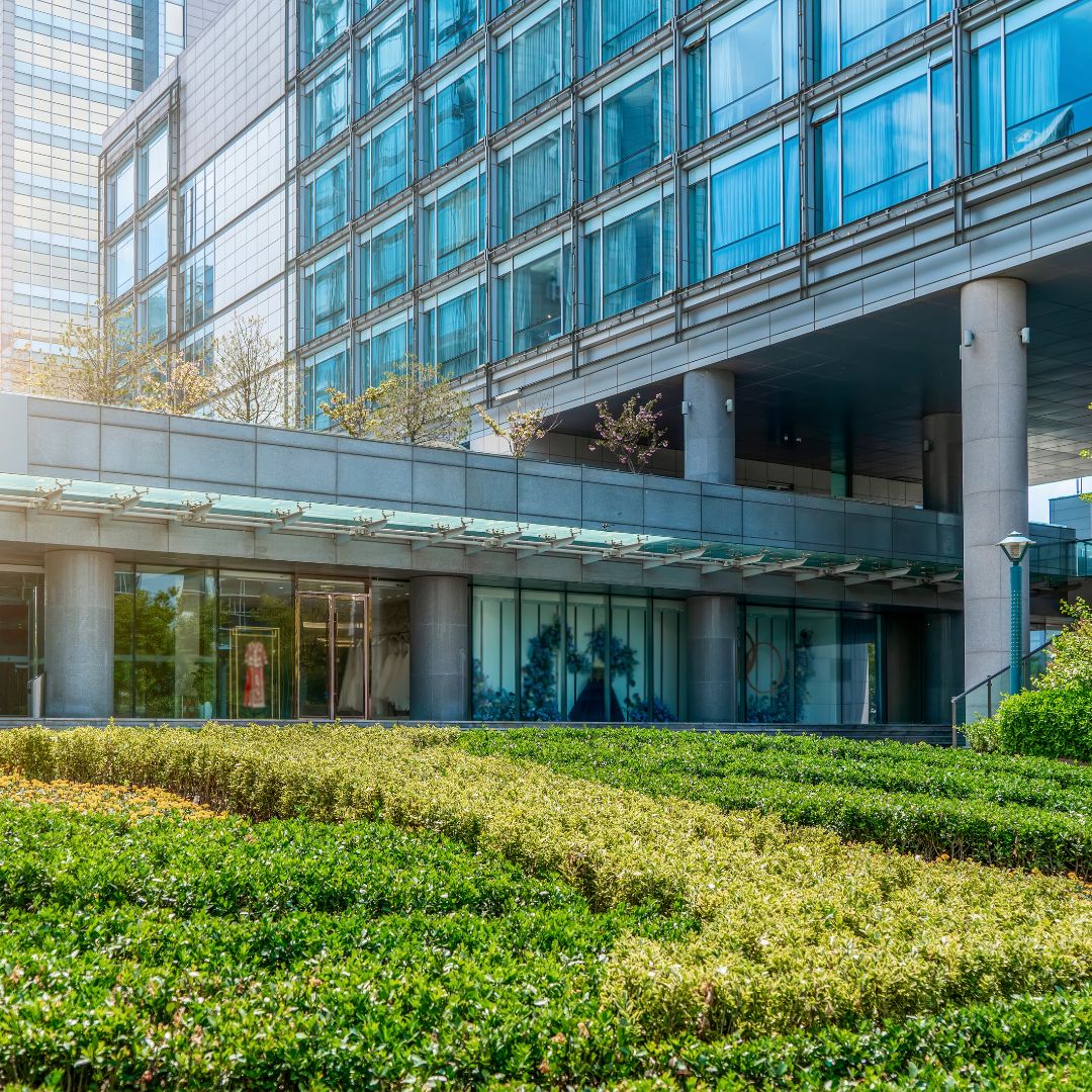 Modern glass office building with green landscaping and blue-tinted windows